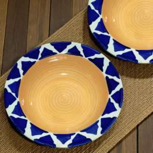 blue and yellow Moroccan-style ceramic psta plates on light wooden surface, with a bamboo mat